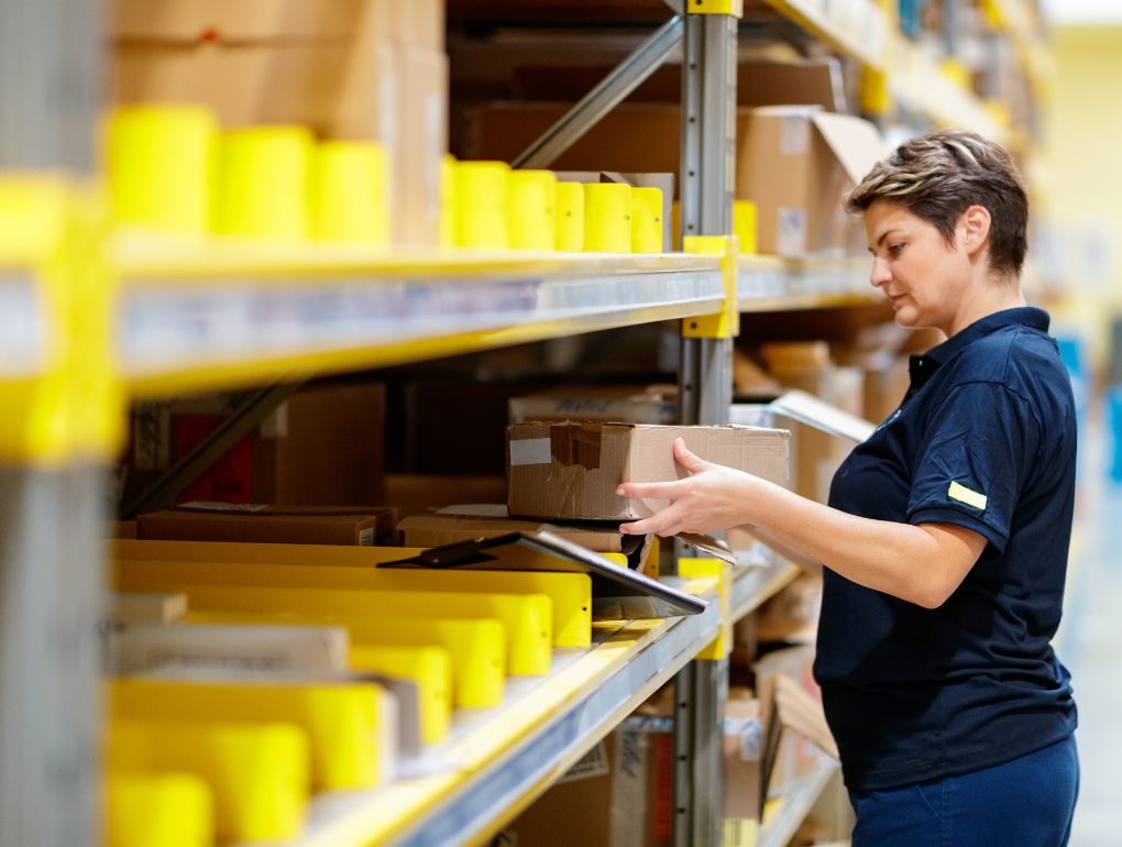 Woman looking at box on warehouse racking